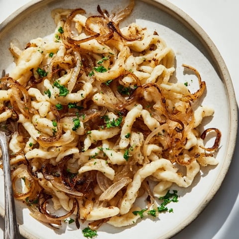 Zarte hausgemachte Spaetzle mit süßen, goldenen Zwiebeln und Butter.