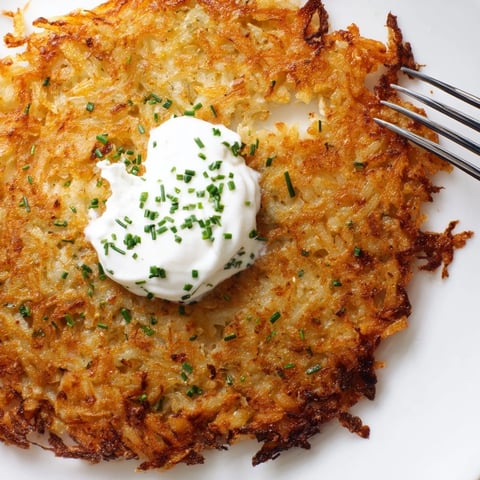 Krosse Kartoffelpuffer mit einer cremigen Sour-Cream-Dip serviert, perfekt als Vorspeise.